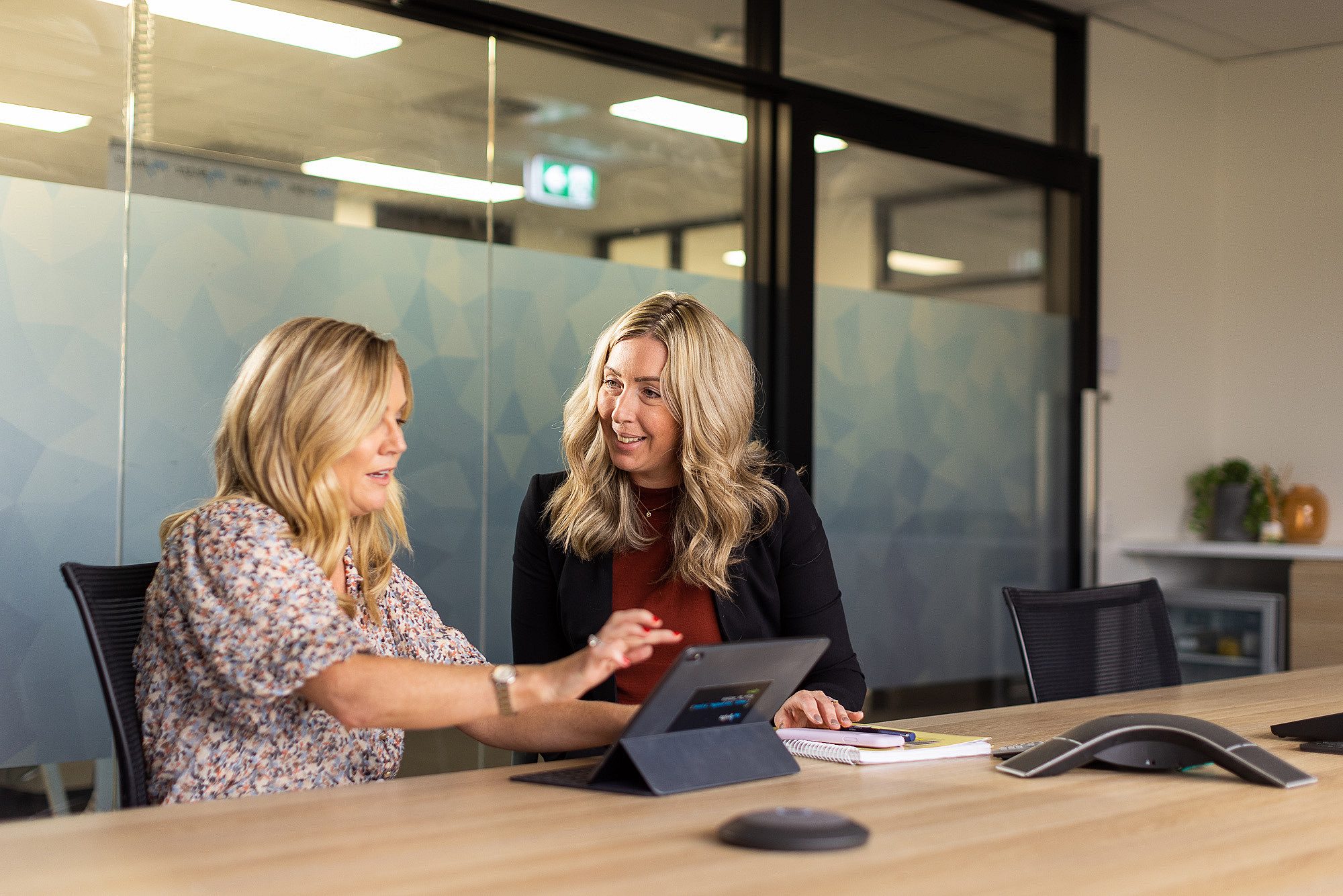 Two people in a meeting room looking at a computer
